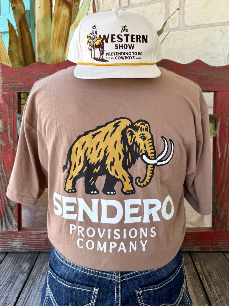 Men's tan mocha Sendero Provisions Co. Mammoth short sleeve tee with bold full-color gold black woolly mammoth back graphic and white SENDERO PROVISIONS COMPANY block letter text, back view styled with jeans and tooled leather belt — Blair's Western Wear Marble Falls TX