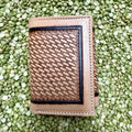 Natural tan leather trifold wallet with basketweave tooling, a dark rectangular border, decorative edge stamping, and stitched edges — Blair's Western Wear Marble Falls TX