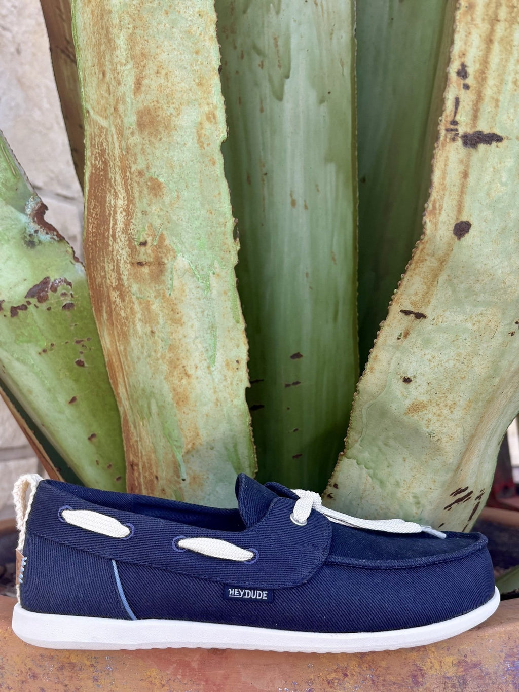  Full side — navy twill, cream rope lace bow, oval vamp keeper, HEYDUDE patch, white EVA sole