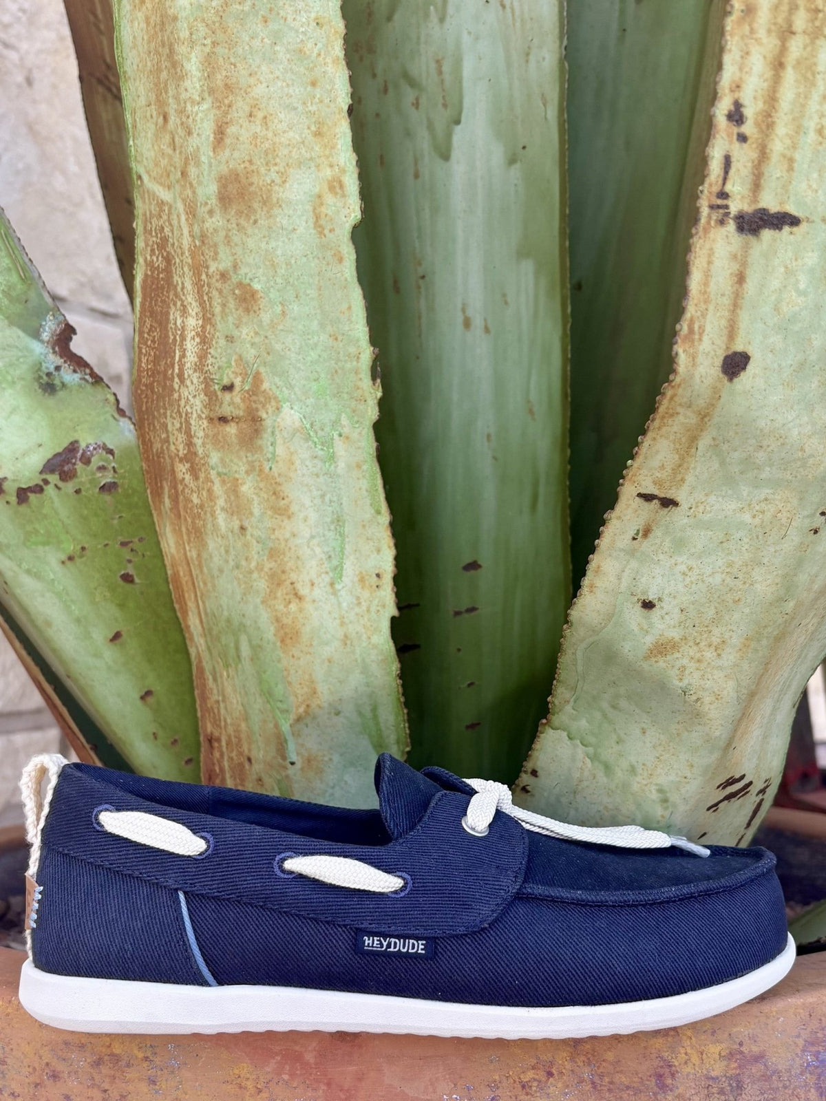  Full side — navy twill, cream rope lace bow, oval vamp keeper, HEYDUDE patch, white EVA sole