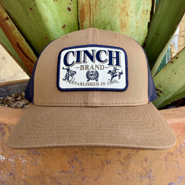 Tan structured trucker cap with navy mesh back and white woven Cinch Brand Established in 1996 patch with rodeo graphics on front panel — Blair's Western Wear Marble Falls TX