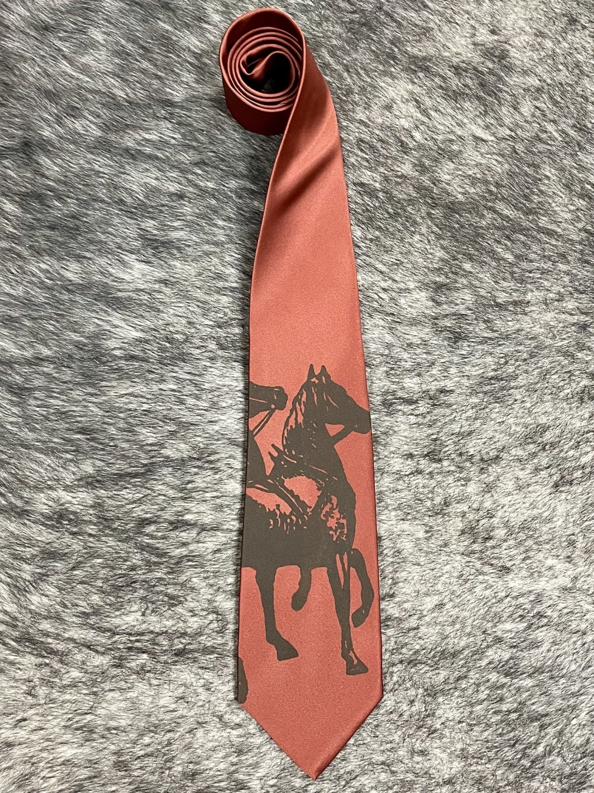 Men's cinnamon terracotta satin necktie with tonal dark brown rearing horse and rider silhouette print, smooth finish, standard width pointed tip — Blair's Western Wear Marble Falls TX
