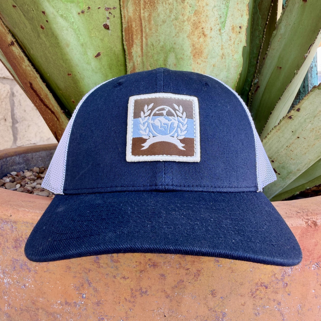 Navy structured kids trucker cap with white mesh back and square Cinch globe and laurel crest woven patch
