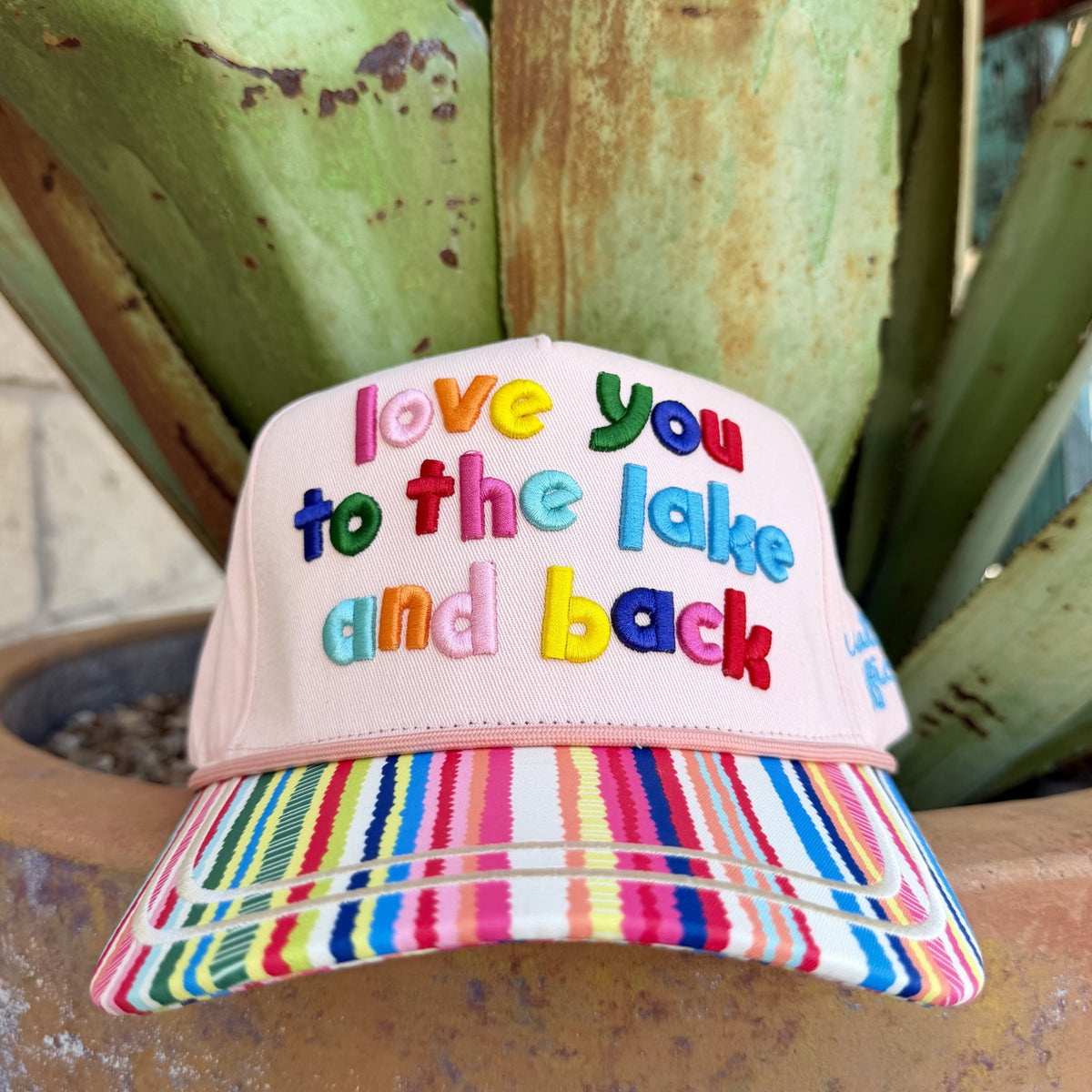 Pink cap with raised multicolor “love you to the lake and back” embroidery and a curved rainbow-striped brim — Blair's Western Wear Marble Falls TX