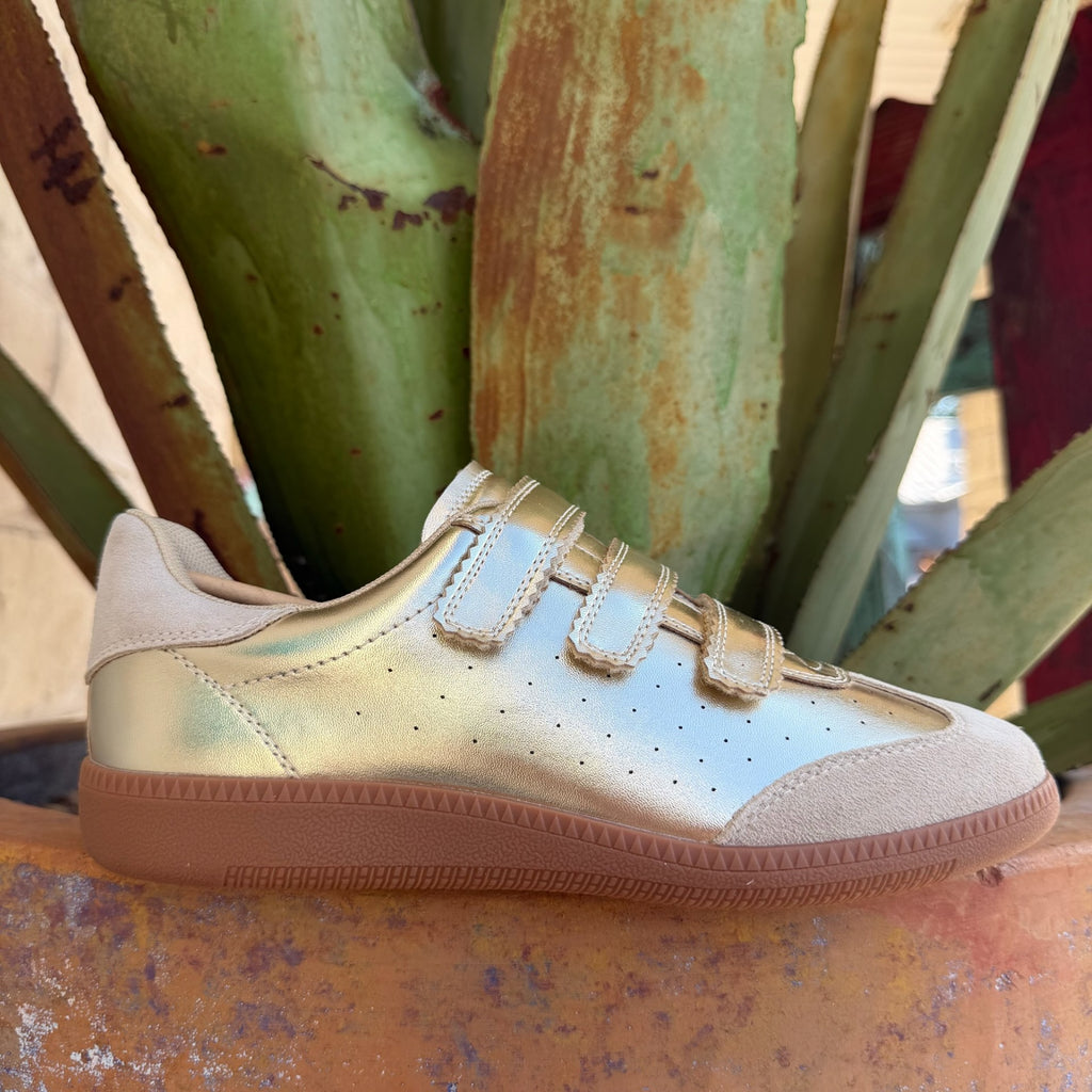 Women's metallic gold low-top sneaker with beige suede panels, velcro closure, and chunky gum sole — Blair's Western Wear Marble Falls TX
