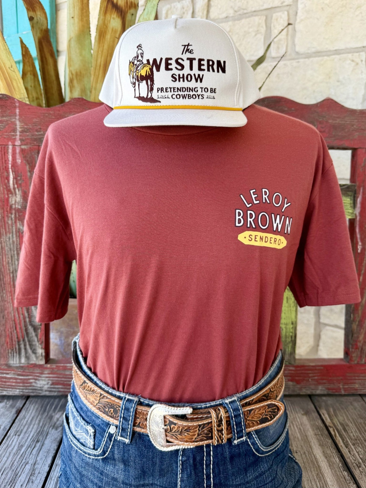 Men's brick red Sendero Provisions Co. Leroy Brown short sleeve tee with white yellow Leroy Brown Sendero chest badge, front view styled with jeans and tooled leather belt — Blair's Western Wear Marble Falls TX