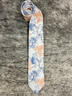 A rolled-up necktie with a white base and a watercolor-style floral pattern in blue and peach, laid flat on a gray faux fur background.