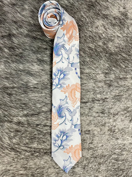 A rolled-up necktie with a white base and a watercolor-style floral pattern in blue and peach, laid flat on a gray faux fur background.