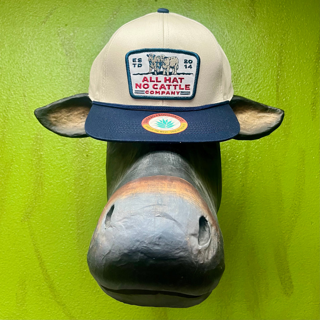 All Hat No Cattle Co. Trucker Hat in White/Navy, embroidered longhorn patch on structured front panel, with adjustable snapback closure for custom fit - ALL HAT NO CATTLE. Available at Blair's Western Wear, Marble Falls, TX.