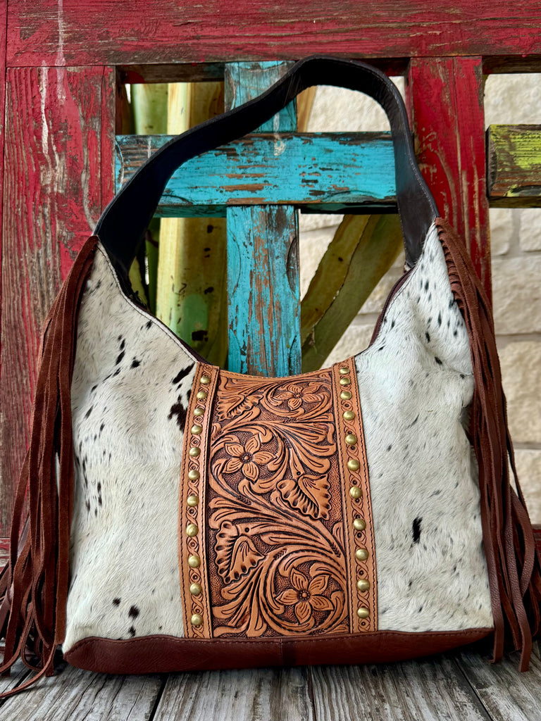 American Darling hide purse with tooled leather floral panel in brown/white, made with durable cowhide, with a wide tooled shoulder strap for comfortable carry – ADBGI1121. Available at Blair's Western Wear, Marble Falls, TX.
