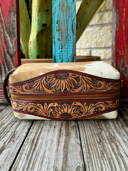 American Darling shave kit hair-on travel bag in brown and white, crafted with durable hair-on hide, with hand-tooled sunflower leather accents for added structure and style — ADBG994. Available at Blair's Western Wear, Marble Falls, TX.