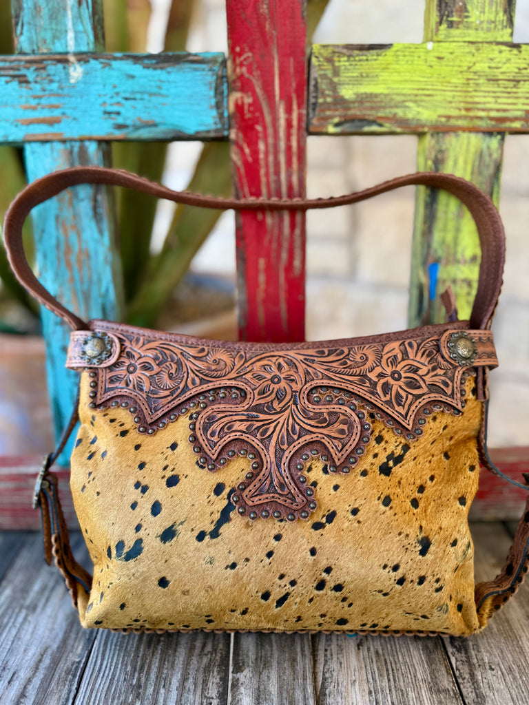 American Darling tool hide purse in tan and brown, genuine hair-on hide front with natural speckled pattern, featuring hand-tooled leather overlay and antique-style stud accents - ADBG713D. Available at Blair's Western Wear, Marble Falls, TX.