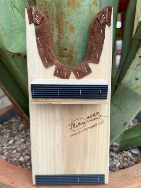 Blair’s Boot Jack - JACK BLAIR -  Expertly crafted from durable natural wood and lined with soft suede for added protection, this piece features our name along a cool boot stitch engraving for a refined Western touch. Designed for daily use, it offers both practicality and timeless style for any boot owner. Available at BLAIR'S Western Wear located in Marble Falls TX.