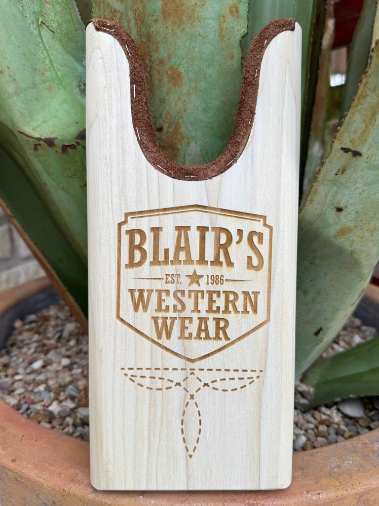 Blair’s Boot Jack - JACK BLAIR -  Expertly crafted from durable natural wood and lined with soft suede for added protection, this piece features our name along a cool boot stitch engraving for a refined Western touch. Designed for daily use, it offers both practicality and timeless style for any boot owner. Available at BLAIR'S Western Wear located in Marble Falls TX.