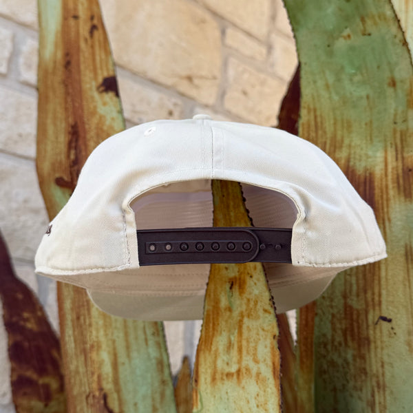 An off-white snapback cap shown from the back, featuring a brown plastic adjustment strap