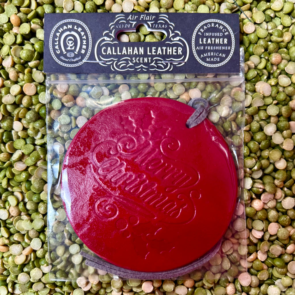 Callahan Leather air freshener round leather ornament in red, made from fragrance-infused leather, with a sturdy leather tie for easy hanging - AFRDCHRISTREDLTH. Available at Blair's Western Wear, Marble Falls, TX.