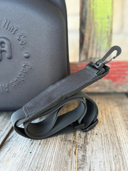 The Cactus Ally Hat Company Cap Carrier keeps your favorite caps protected and organized on the go. Designed in sleek black, it holds 4–5 caps securely and includes a built-in sunglasses case for added convenience. Carry it your way with both handheld and shoulder strap options—perfect for travel, rodeos, or everyday use. Available at BLAIR'S Western Wear located in Marble Falls, TX 
