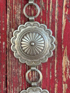 Stacked round silver conchos with deeply stamped sunburst and floral engraving, linked by open rings — this belt carries the weight of real Western artistry. The scalloped edges and layered detailing give it a heritage feel that pairs effortlessly with everything from denim to dresses