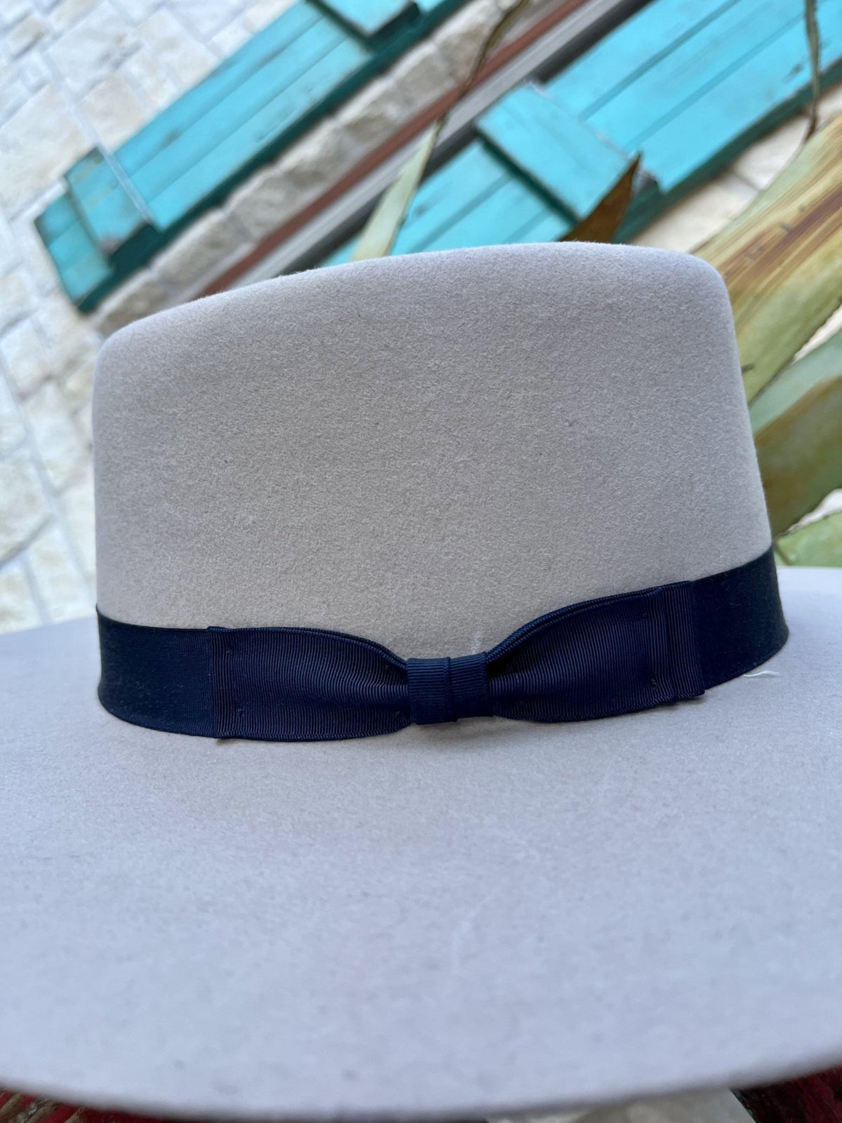 Bone wool felt hat showing the ribbed texture and tailored bow of its wide navy ribbon hatband — Blair's Western Wear Marble Falls TX