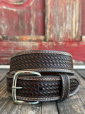 A dark brown woven leather belt with a silver buckle, coiled on a rustic wooden surface with a weathered red wooden background. Available at Blair's Western Wear located in Marble Falls TX