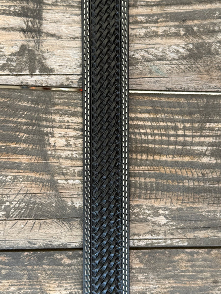 A close-up of a black woven leather belt, featuring white contrast stitching , laid flat on a rustic wooden plank background. Available at Blair's Western Wear, Marble Falls, TX