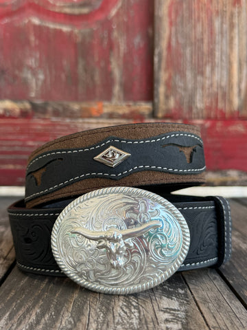 A western-style leather belt coiled on a rustic wooden surface, featuring a large engraved silver buckle with a steer design, a dark brown leather strap, and a black leather section with white stitching and a small diamond-shaped logo. It also features longhorn cutouts. Available at BALIR'S Western Wear located in Marble Falls TX 