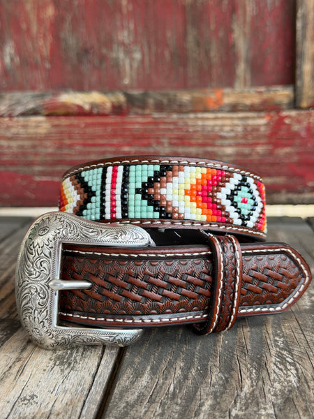 Dark brown basketweave-tooled leather is inlaid with a vivid Aztec-inspired beaded stripe in turquoise, red, orange, black, and white, finished with cream stitching and an ornate engraved silver buckle — a bold pop of southwestern color on a classically crafted belt. Available at BLAIR'S Western Wear located in Marble Falls TX