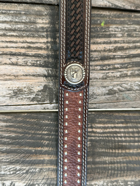 Western belt featuring a dark brown hand-tooled basketweave pattern with contrasting white stitching. The center is accented with distressed brown leather and two rows of antique silver studs for added detail. It also features 2 Praying Cowboy Stud Conchos. Finished with a polished silver roller buckle and matching leather keeper, this belt is built for durable everyday wear.Available at Blair's Western Wear, Marble Falls, TX
