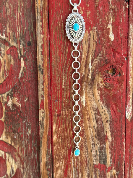A1308233 — Kid's Turquoise Concho Chain Western Belt Full silver concho chain belt with repeating oval silver conchos featuring engraved petal/sunburst detail, rope edge border, and turquoise stone center in each. Silver O-ring links connect each concho. Adjustable silver O-ring chain tail with small turquoise stone drop tip. Available at Blair's Western Wear located in Marble Falls TX 