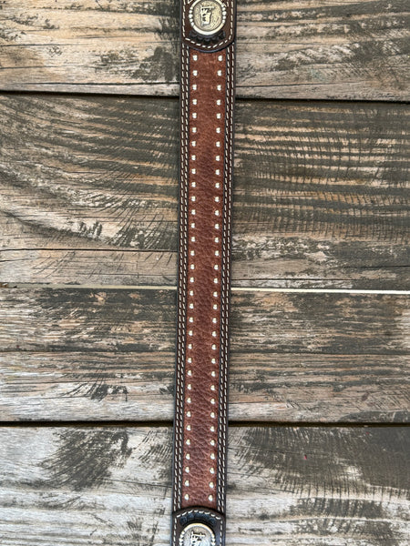 Western belt featuring a dark brown hand-tooled basketweave pattern with contrasting white stitching. The center is accented with distressed brown leather and two rows of antique silver studs for added detail. It also features 2 Praying Cowboy Stud Conchos. Finished with a polished silver roller buckle and matching leather keeper, this belt is built for durable everyday wear.Available at Blair's Western Wear, Marble Falls, TX
