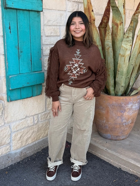 Ladies Aztec Sweater crafted in a warm brown knit, featuring a bold Aztec design in mint and natural tones along with soft fringe detailing down the sleeves. Its relaxed fit and textured finish make it perfect for pairing with your favorite denim or cords, all while keeping you stylish and comfortable through the cooler seasons. Available at BLAIR'S Western Wear located in Marble Falls TX.
