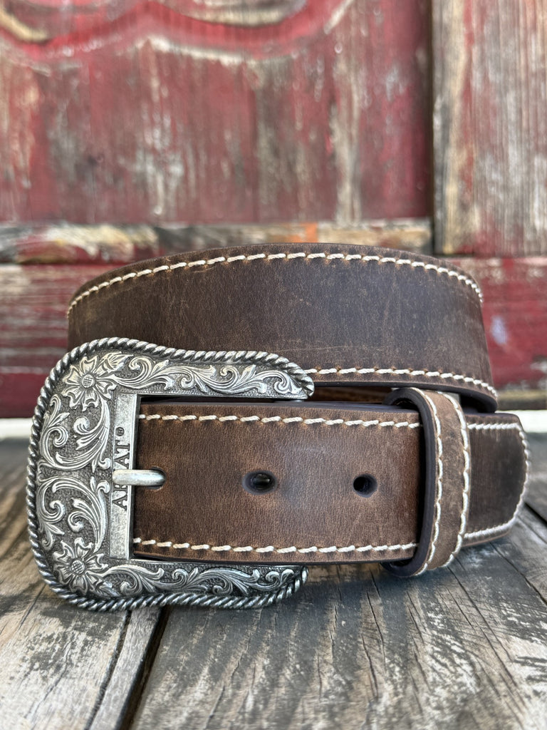 Rich bomber brown genuine leather belt with cream heavy edge stitching along both sides, finished with a large ornate silver floral scroll buckle with rope-edge border and flower corner accents. Classic Western craftsmanship with a refined, polished finish. Shop at Blair's Western Wear — blairswesternwear.com.

