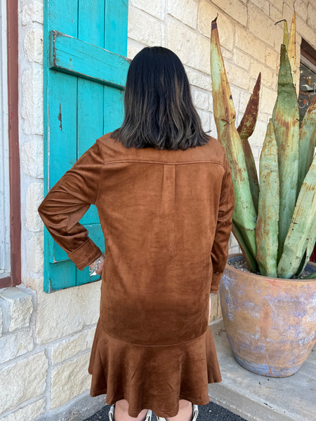 This Ivy Jane Suede Shirtdress in chestnut blends classic western charm with soft, everyday comfort. Made from rich faux suede, it features a collared neckline, button-front detail, a relaxed fit, and a flirty ruffle hem. With convenient pockets and a warm, earthy tone, it’s the perfect piece for effortless fall styling. Available at BLAIR's Western Wear located in Marble Falls, TX. 
