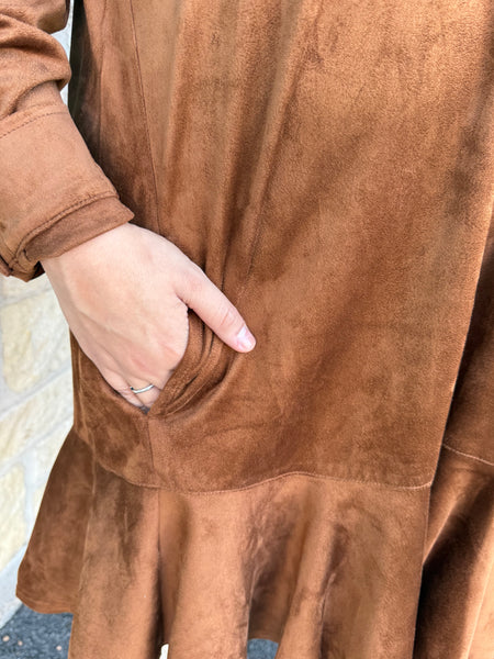 This Ivy Jane Suede Shirtdress in chestnut blends classic western charm with soft, everyday comfort. Made from rich faux suede, it features a collared neckline, button-front detail, a relaxed fit, and a flirty ruffle hem. With convenient pockets and a warm, earthy tone, it’s the perfect piece for effortless fall styling. Available at BLAIR's Western Wear located in Marble Falls, TX. 
