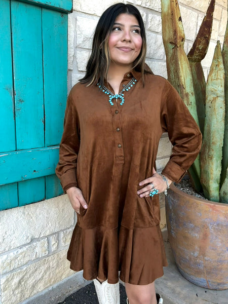 This Ivy Jane Suede Shirtdress in chestnut blends classic western charm with soft, everyday comfort. Made from rich faux suede, it features a collared neckline, button-front detail, a relaxed fit, and a flirty ruffle hem. With convenient pockets and a warm, earthy tone, it’s the perfect piece for effortless fall styling. Available at BLAIR's Western Wear located in Marble Falls, TX. 