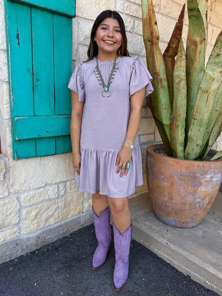 This shimmery lavender Ivy Jane dress brings easy feminine charm with its flutter sleeves, soft knit fabric, and flouncy ruffle hem. Perfect for everyday wear or a dressed-up look, it’s a comfortable standout piece for any wardrobe. Available at BLAIR’S Western Wear located in Marble Falls, TX.