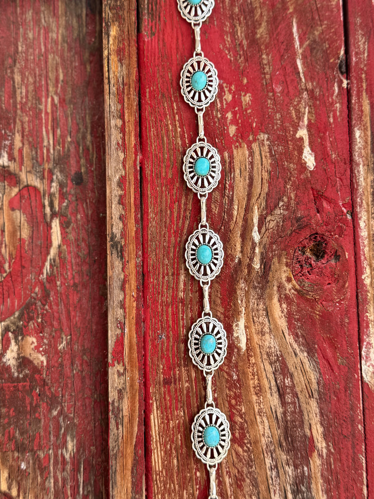 Petite oval silver conchos with scalloped sunburst-stamped edges and a vibrant turquoise stone center, linked by a delicate silver chain — this belt brings understated Southwestern charm to any look. Dainty enough for everyday wear, distinctive enough to turn heads at any western occasion. Available at Blair's Western Wear located in Marble Falls TX 
