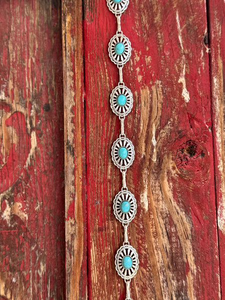 Petite oval silver conchos with scalloped sunburst-stamped edges and a vibrant turquoise stone center, linked by a delicate silver chain — this belt brings understated Southwestern charm to any look. Dainty enough for everyday wear, distinctive enough to turn heads at any western occasion. Available at Blair's Western Wear located in Marble Falls TX 
