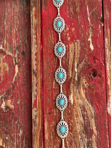 Petite oval silver conchos with scalloped sunburst-stamped edges and a vibrant turquoise stone center, linked by a delicate silver chain — this belt brings understated Southwestern charm to any look. Dainty enough for everyday wear, distinctive enough to turn heads at any western occasion. Available at Blair's Western Wear located in Marble Falls TX 
