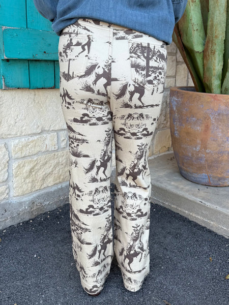 These Lucky & Blessed Western Print Trousers bring vintage cowboy vibes to any outfit. Made with a soft, lightweight fabric and a comfortable mid-rise fit, they feature an all-over brown rodeo scene print on a cream background. Finished with a flattering bootcut leg, these trousers pair perfectly with your favorite denim tops, graphic tees, or boots for an effortless western look. Available at BLAIR'S Western Wear located in Marble Falls TX.
