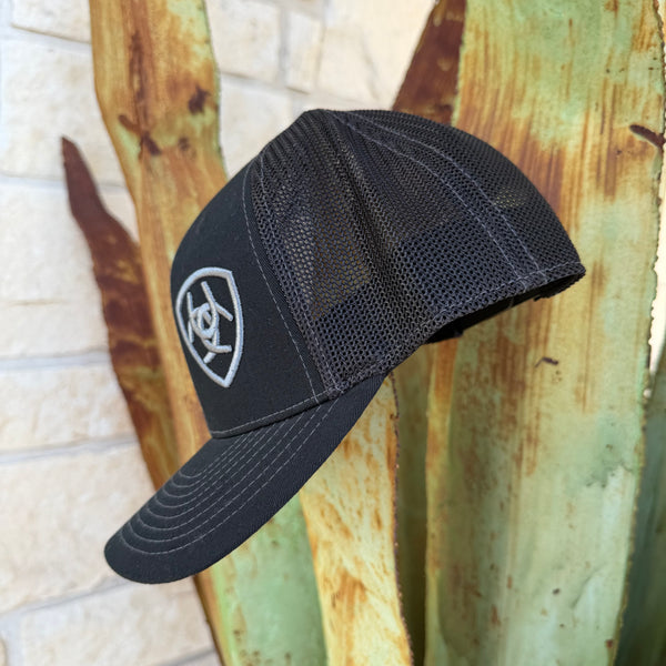 A black trucker-style baseball cap with a mesh back and a gray shield logo on the front,