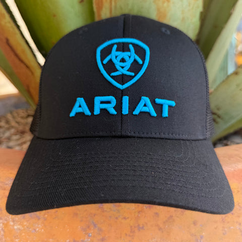 A black trucker-style cap with a bright blue embroidered shield logo and the word 'ARIAT' on the front