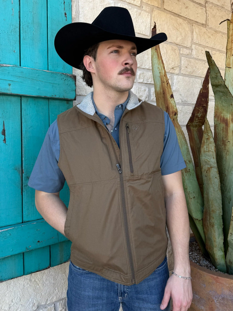 Men’s Ariat canvas vest in tan, featuring a sherpa-lined collar for warmth and secure zip chest pocket for storage – 10028416. Available at Blair’s Western Wear, Marble Falls, TX.