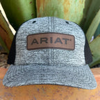 A heather gray trucker hat with black mesh side panels and a brown leather patch on the front that reads ARIAT, 