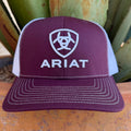 A maroon and white trucker hat with white embroidered Ariat logo and text, 