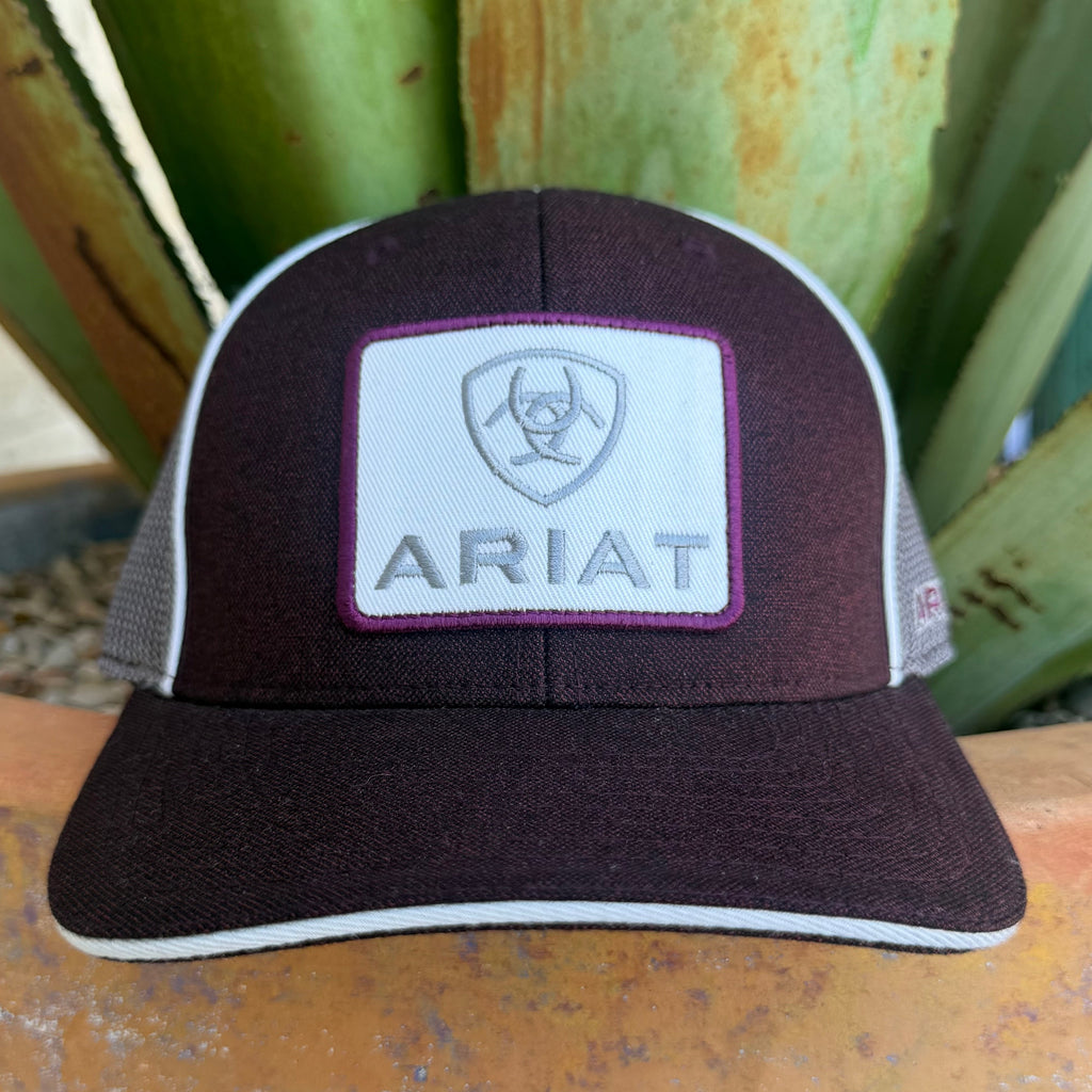 A dark burgundy and white ARIAT trucker hat with a white front patch featuring the brand logo