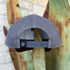 A gray mesh-back trucker cap shown from the back, featuring an adjustable dark gray strap with a black patch displaying the ARIAT logo