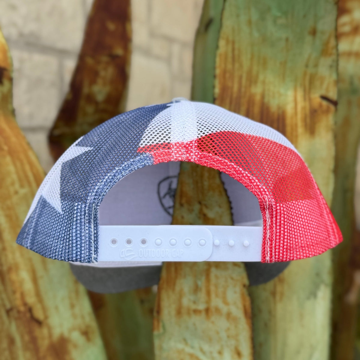 A trucker-style baseball cap with a red, white, and blue Texas flag-inspired pattern on the back mesh 