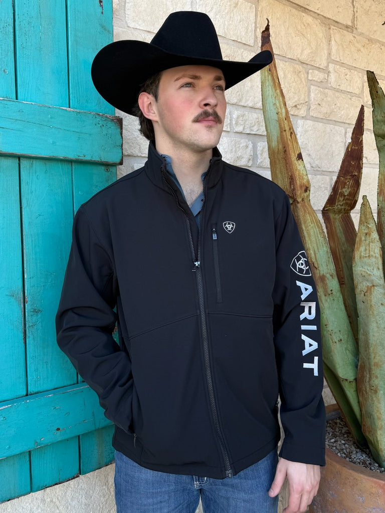 Men’s Ariat softshell jacket in black, wind- and water-resistant stretch fabric, fleece-lined for warmth, with zip pockets and Ariat logo on sleeve - 10062578. Available at Blair’s Western Wear, Marble Falls, TX.