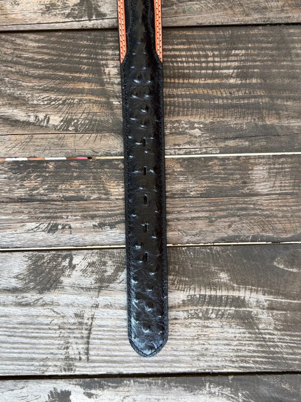 Black ostrich print leather with tan leather trim edges and cream contrast stitching, finished with a large engraved silver western buckle — an exotic, eye-catching belt with refined western character. Find it at Blair's Western Wear in Marble Falls, TX or online at blairswesternwear.com.